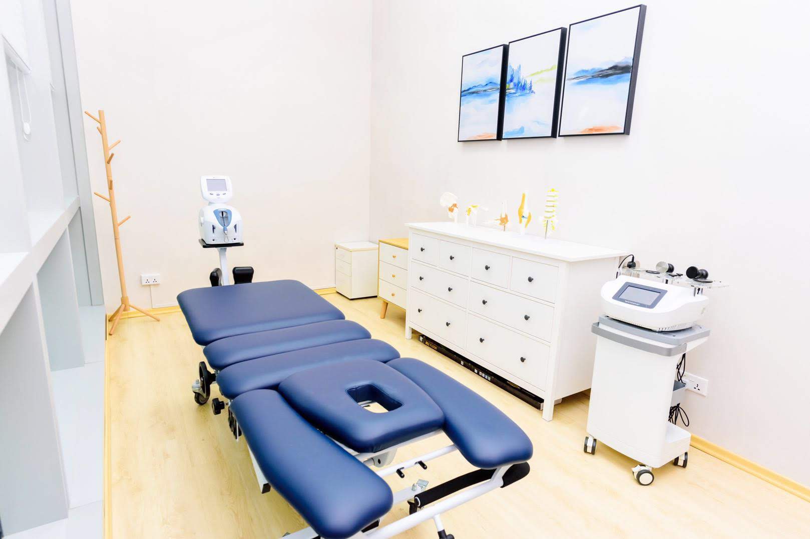 Inside Advanced Physio Care clinic, blue traction table. white room and paintings